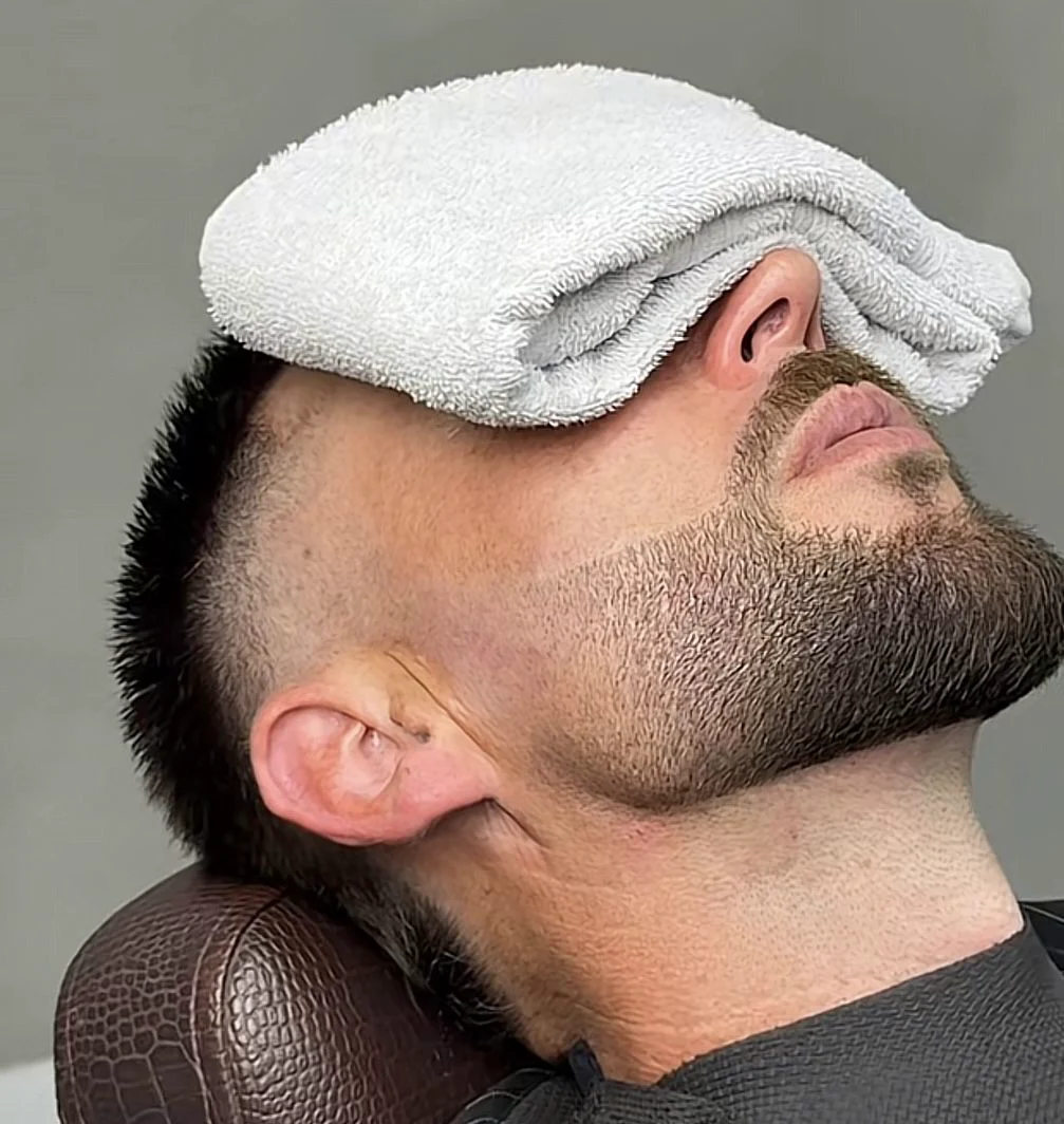 Clientes satisfechos en El Pulso Barber's — ambiente lujoso con sillones de cuero, iluminación cálida dorada y cortes precisos tipo degradado y barba esculpida