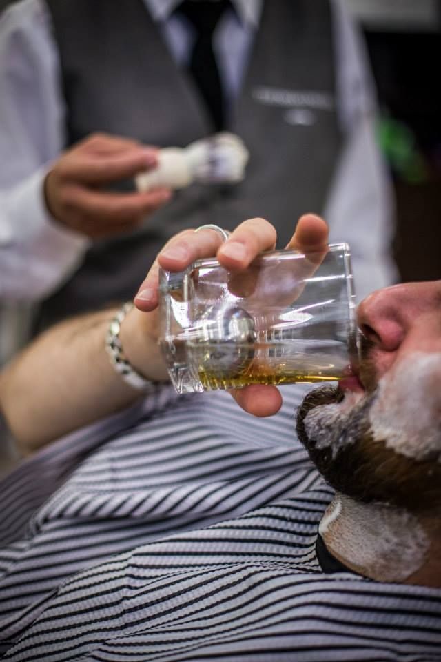 Clientes satisfechos en El Pulso Barber's — ambiente lujoso con sillones de cuero, iluminación cálida dorada y cortes precisos tipo degradado y barba esculpida